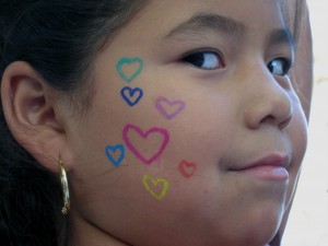 Girl with face painting of hearts on her cheek in celebration of peace.